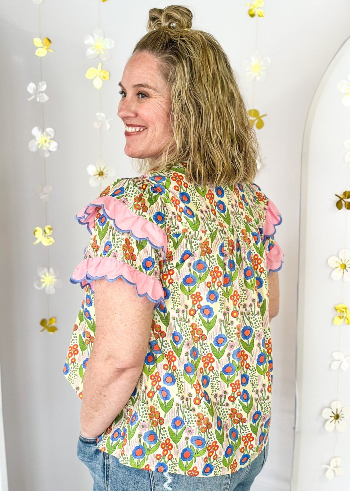 lightweight short sleeve v-neck blouse. Small pink, blue and orange flowers with pink scallop ruffle detail on the sleeve and across the chest. 