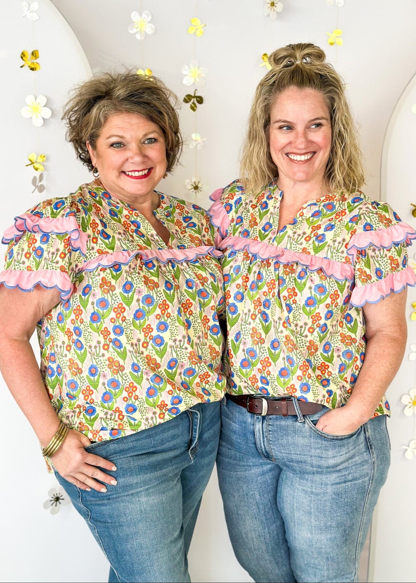 lightweight short sleeve v-neck blouse. Small pink, blue and orange flowers with pink scallop ruffle detail on the sleeve and across the chest. 