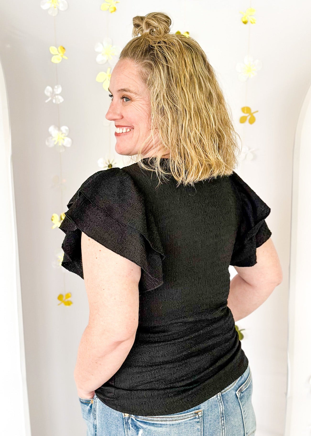 Lightweight textured short sleeve solid black top.  Round neck and ruffle sleeve.  