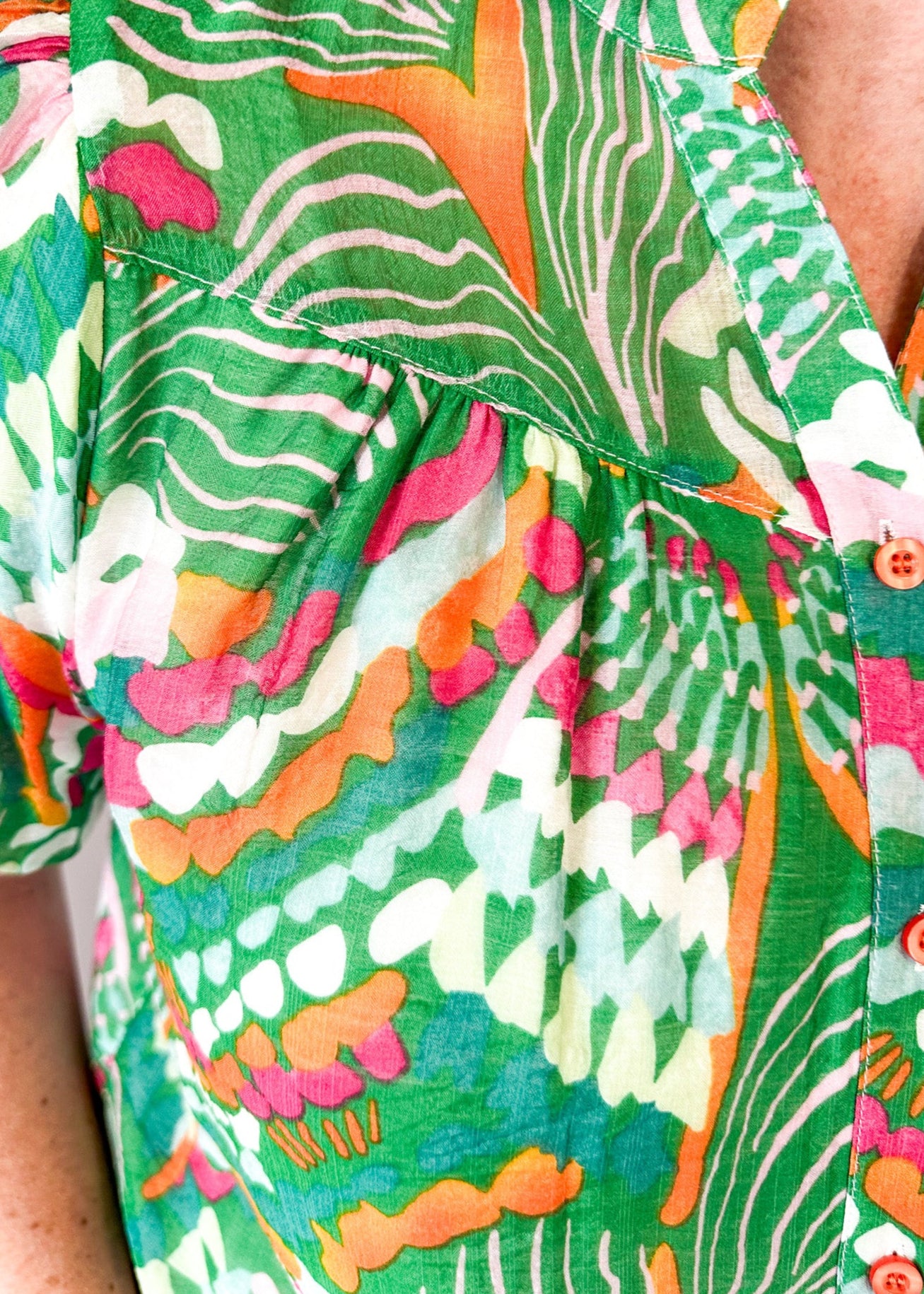 Lightweight short sleeve button up v-neck top.  Tropical print in green, white, pink and orange.  