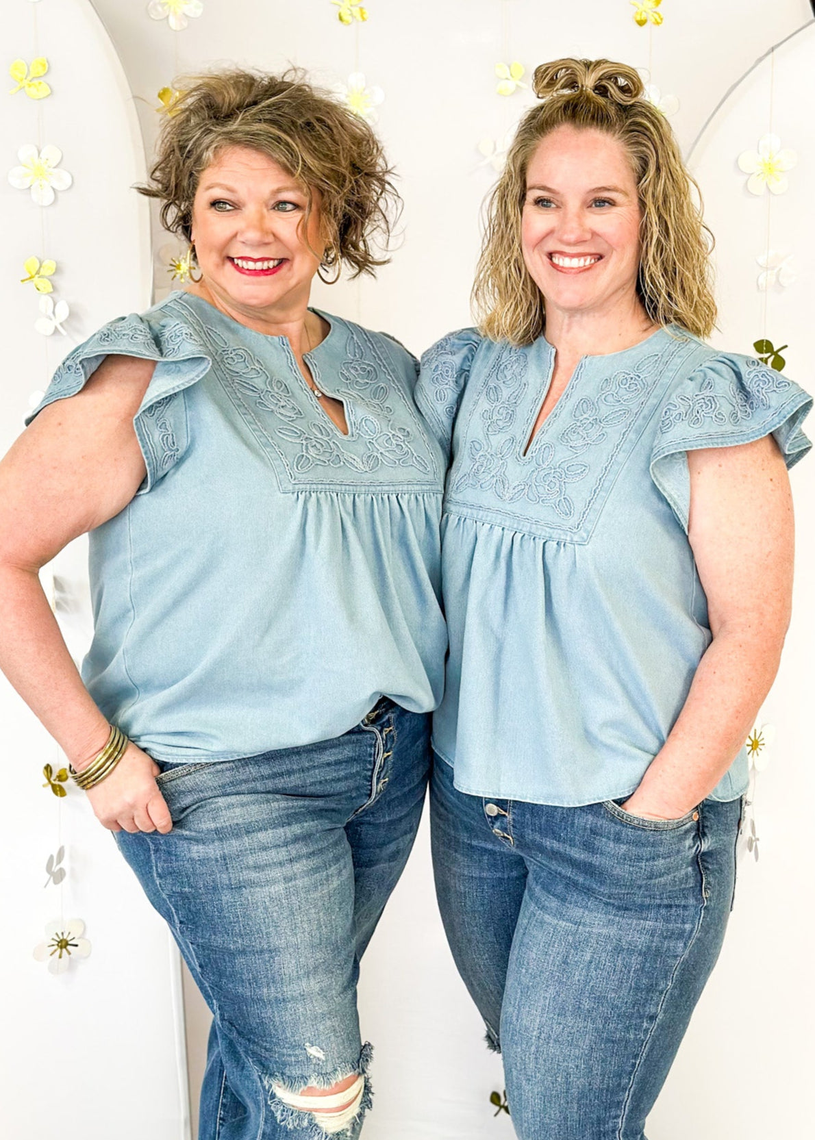 light colored denim top with ruffle short sleeve, v-neck with floral embroidery like detail on top and sleeve