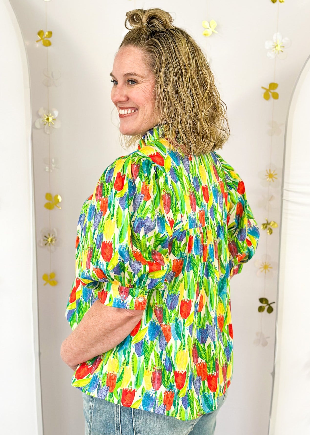 bright tulip print on oversized v-neck short dolman sleeve top w/banded cuff, ruffle around neckline, green leaves, tulips in red, blue purple and yellow