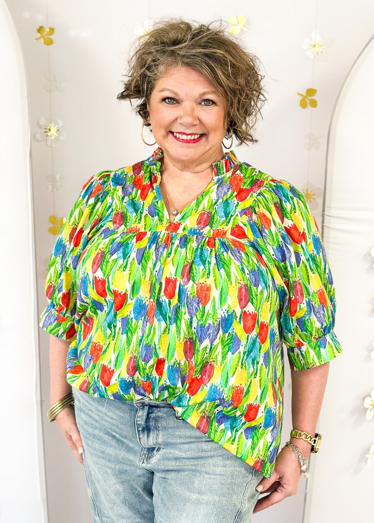 bright tulip print on oversized v-neck short dolman sleeve top w/banded cuff, ruffle around neckline, green leaves, tulips in red, blue purple and yellow