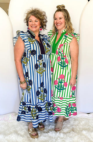 Two women wearing colorful dresses standing against a white background