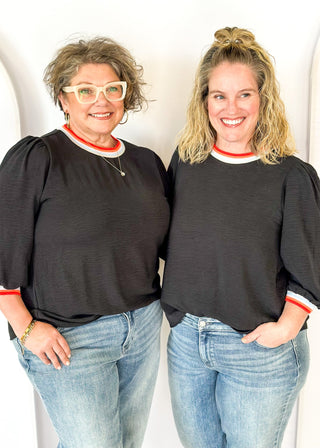 black loose fitting top with 3/4 length sleeve - round neck and cuff have colored banding