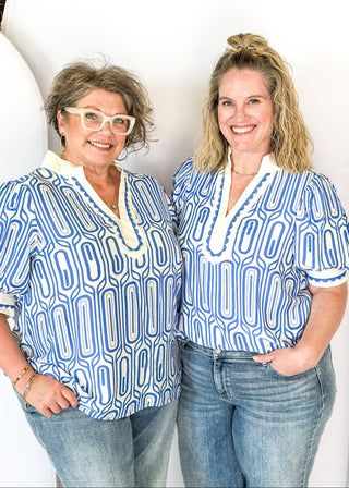 blue geometric pattern on off white puff short sleeve top - off white banding detail around collar and v-neck - blue scallop trim detail around v-neck and on cream banding around cuff
