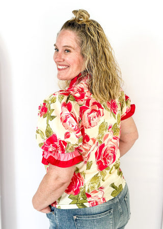 pink and green floral short sleeve top with pink ruffle detail around neckline and cuffs - button snap closure down the front