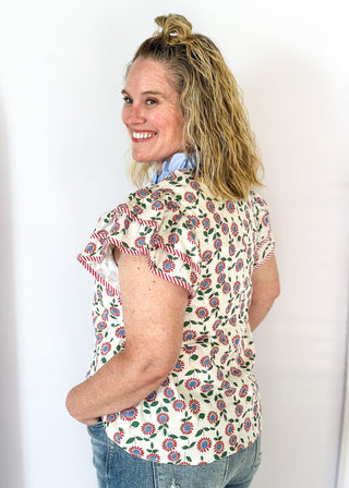 red and blue flowers with green stems on a cream background double ruffle short sleeve top - v-neck - light blue band around ruffle collar and v-neck - candy strip red and white piping detail around double ruffle short sleeves and v-neck