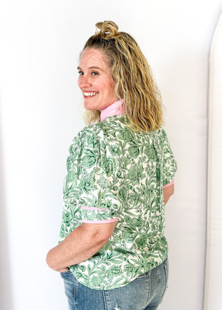 green floral on white elbow length sleeve top - light pink banding detail around collar and v-neck - 2 light pink stripes around cuff