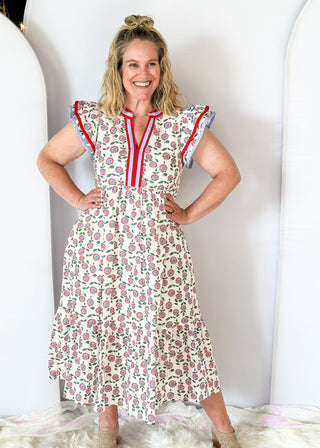 white maxi dress with red and blue flowers and green stems/leaves - tiered - red and blue ribbon trim around v-neckline - and red and blue trim around double ruffle sleeve - pockets