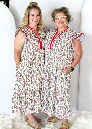 white maxi dress with red and blue flowers and green stems/leaves - tiered - red and blue ribbon trim around v-neckline - and red and blue trim around double ruffle sleeve - pockets