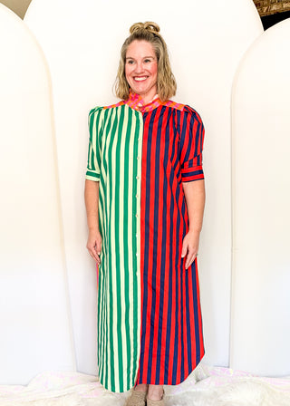 A woman modeling a long-sleeve midi dress with a vertical stripe pattern split down the middle: green and white stripes on the left, red and white stripes on the right, and a pink collar.