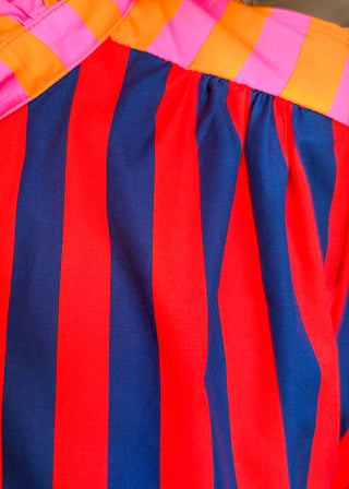 Close-up of a colorful striped garment with vertical red, navy, and pink stripes, plus a contrasting pink, orange, and yellow striped neckline.