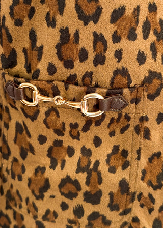 Close-up of a leopard-print fabric with a brown leather strap and gold-tone horsebit hardware across the chest.