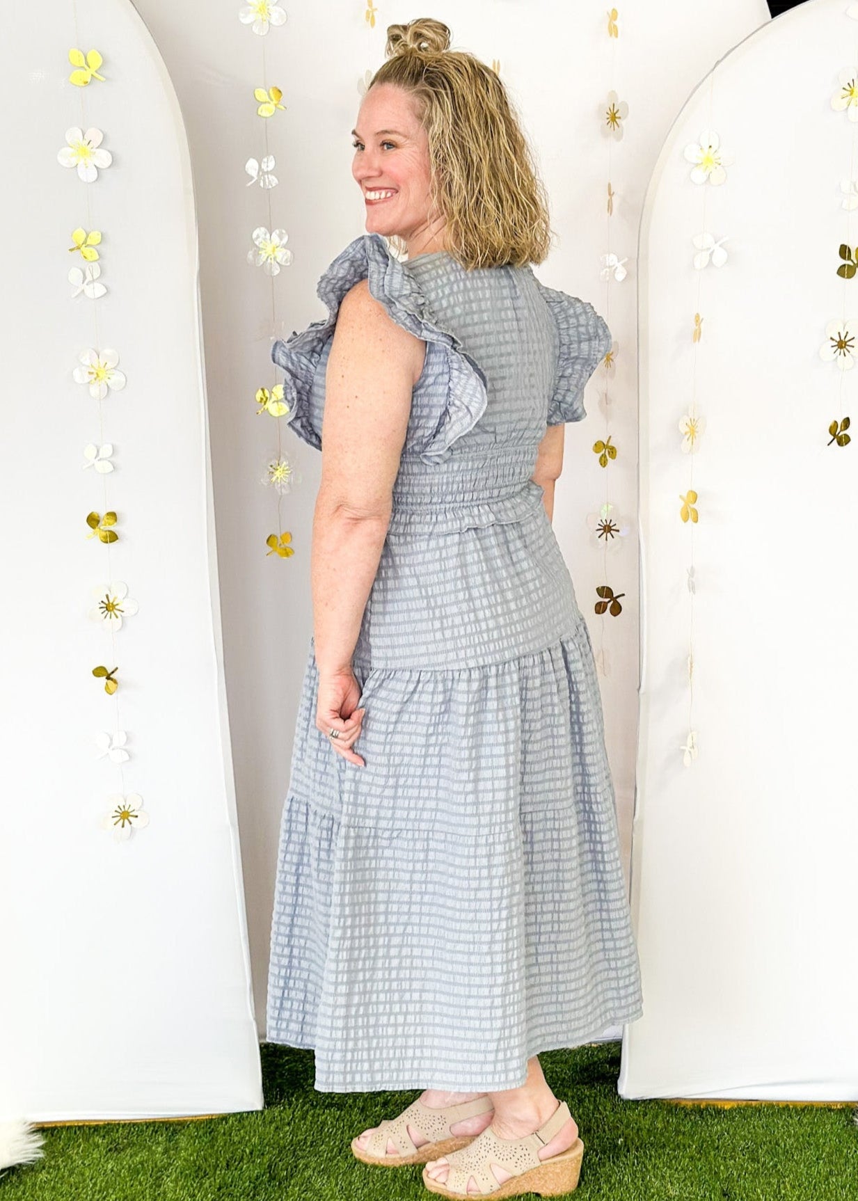 Flutter sleeve, V-neck tiered dress-ruffle detail at waist. Solid color in a blue-gray with seersucker like texture. 