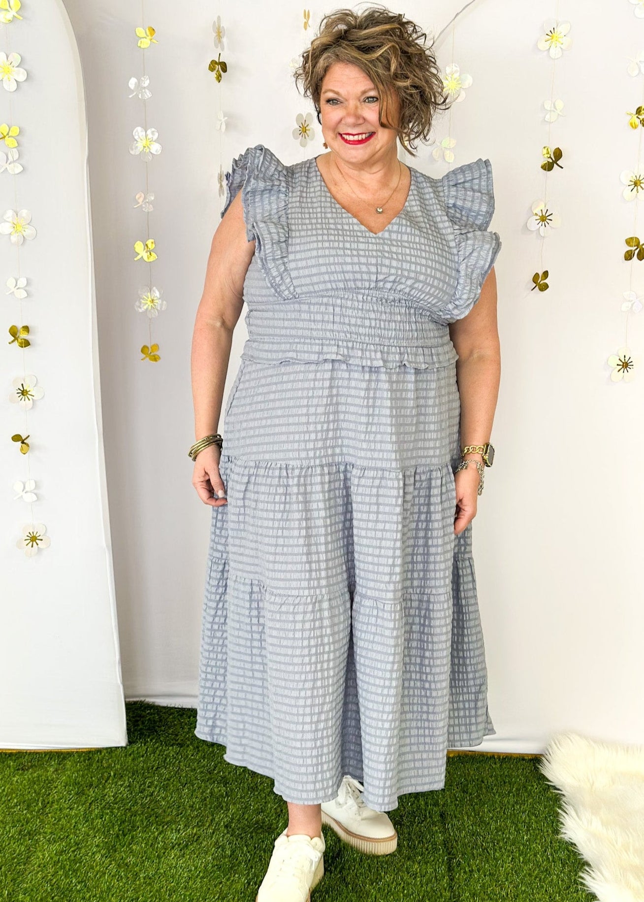 Flutter sleeve, V-neck tiered dress-ruffle detail at waist. Solid color in a blue-gray with seersucker like texture. 