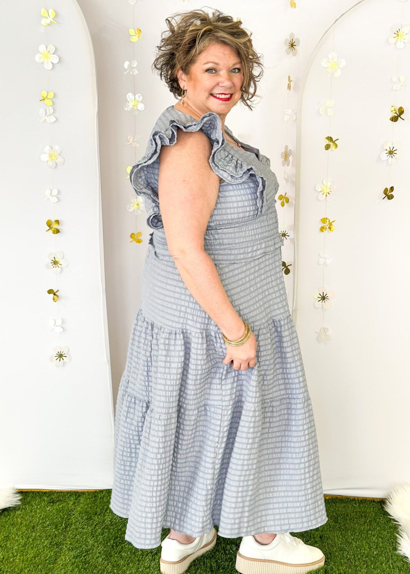 Flutter sleeve, V-neck tiered dress-ruffle detail at waist. Solid color in a blue-gray with seersucker like texture. 