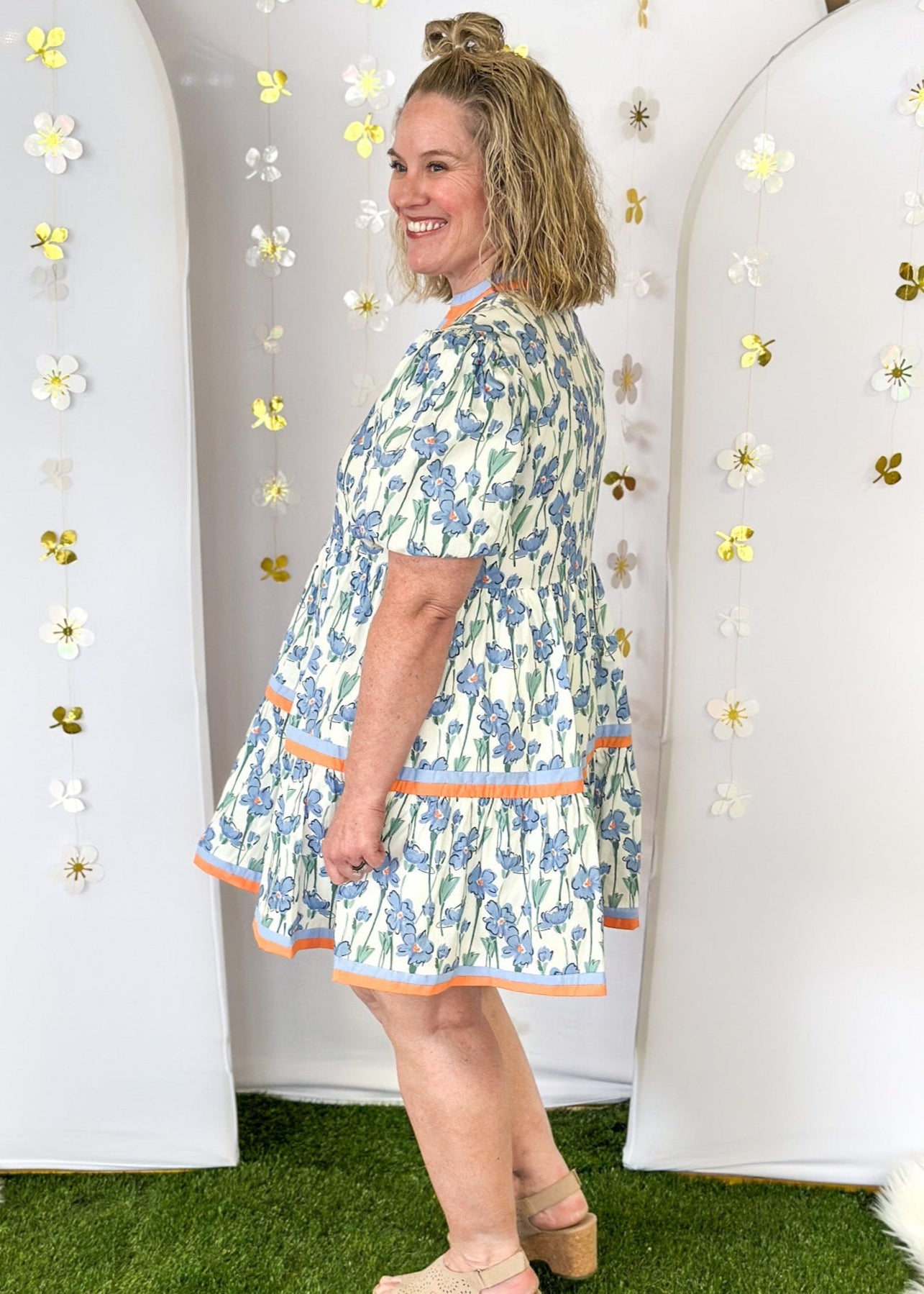 Cream base with cornflower blue wildflowers.  Contrasting color ribbon detail on v-neck, collar, and around the bottom tier.  Puff sleeve-lined;with pockets. 