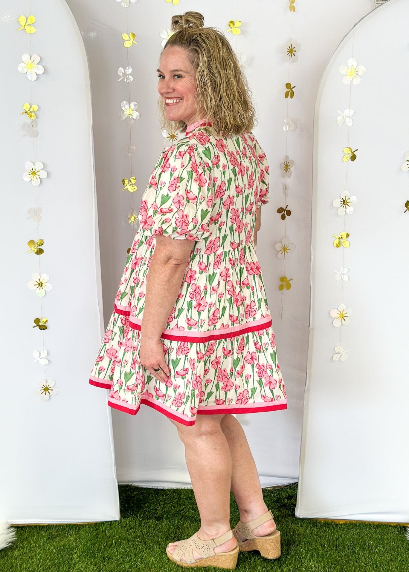 Cream base with pink wildflowers.  pink and dark pink ribbon detail on v-neck, collar, and around the bottom tier.  Puff sleeve-lined;with pockets. 