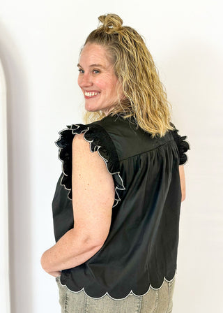  black ruffle sleeve top with scalloped trim in white around the sleeve and bottom - round neck - button closure on the back
