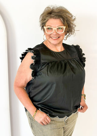  black ruffle sleeve top with scalloped trim in white around the sleeve and bottom - round neck - button closure on the back
