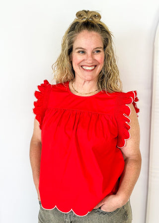red ruffle sleeve top with scalloped trim in white around the sleeve and bottom - round neck - button closure on the back