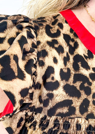 leopard print top with v-neck and short ruffle sleeve - red banding detail around v-neck and neckline - red detail under ruffle sleeve - flowy fit
