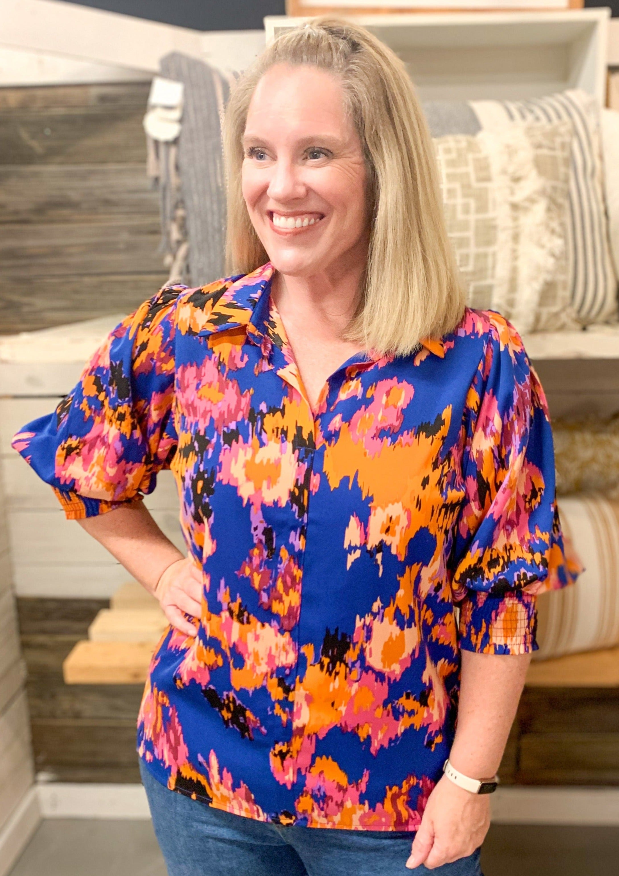 blue pink yellow and orange abstract print satin blouse. Has slight V neck, collar, and a puff sleeve with a wide elastic banded cuff near elbow.