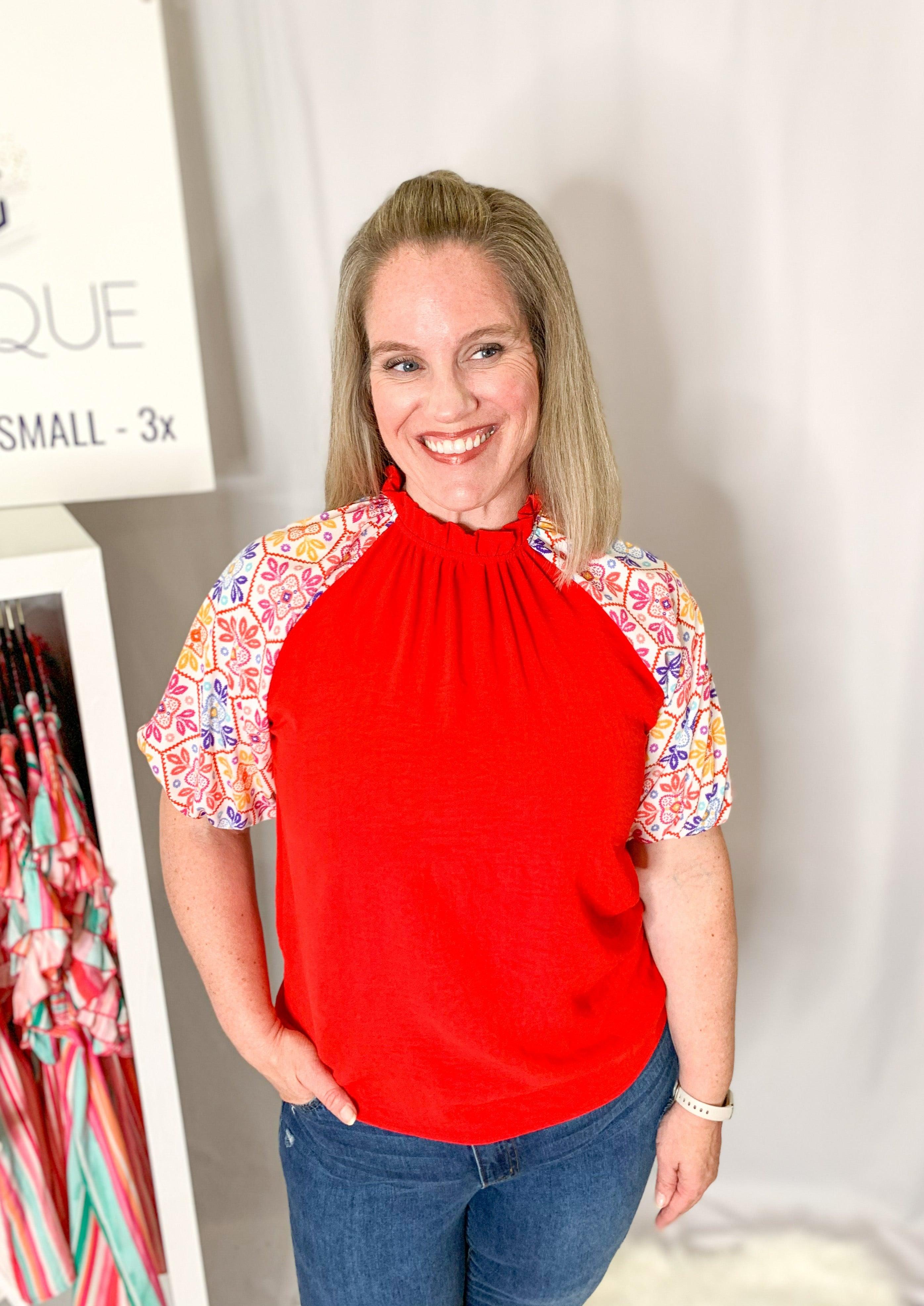 Red top with a ruffle collar. White balloon sleeve with a multicolored printed embroidery pattern.