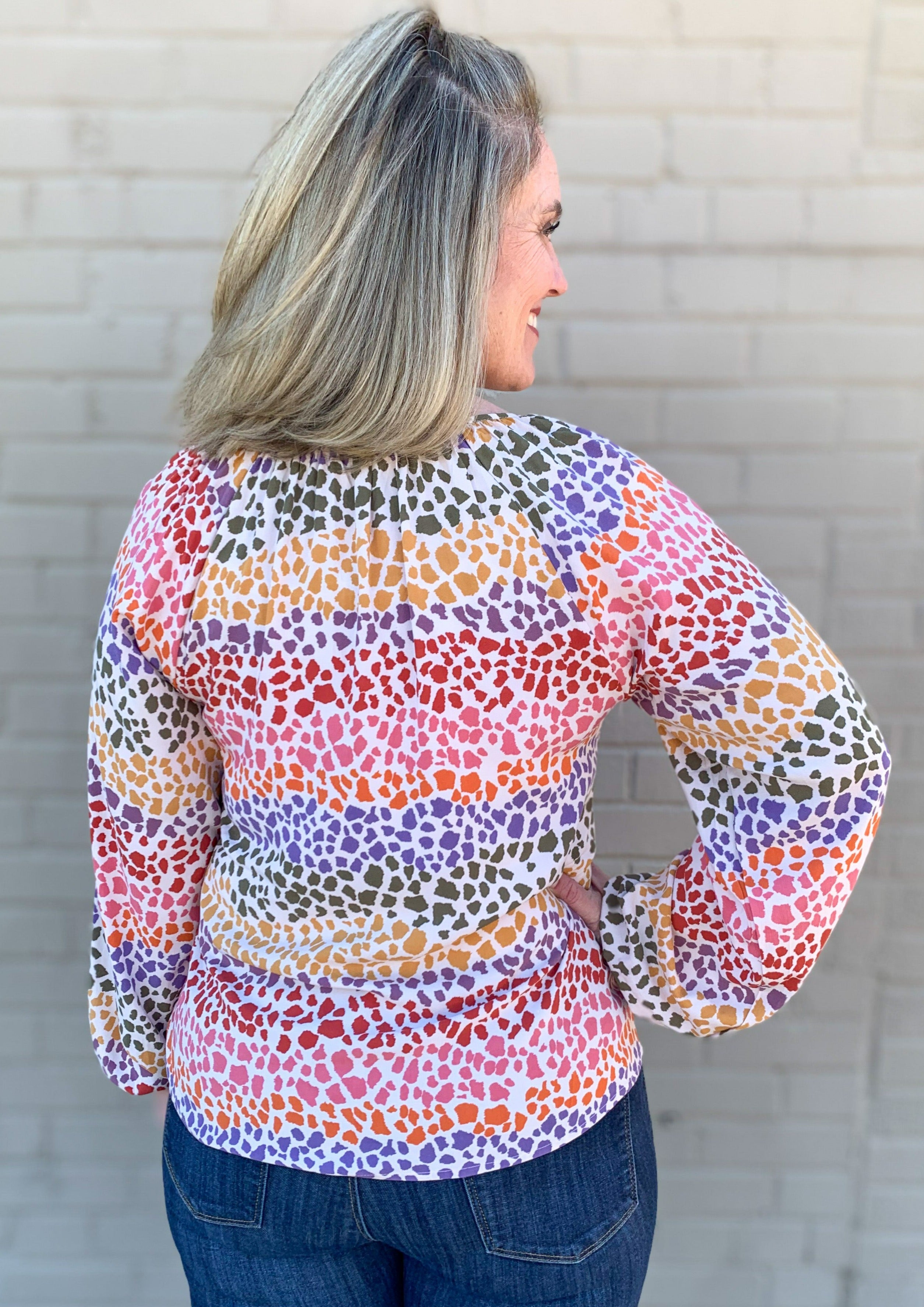 back of Rainbow Animal Print Balloon Sleeve Blouse with V neck. The shirt is white and the animal print is rainbow color blocked.