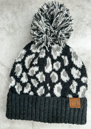 Black cc beanie with white and grey leopard print. White grey and black pom pom on top
